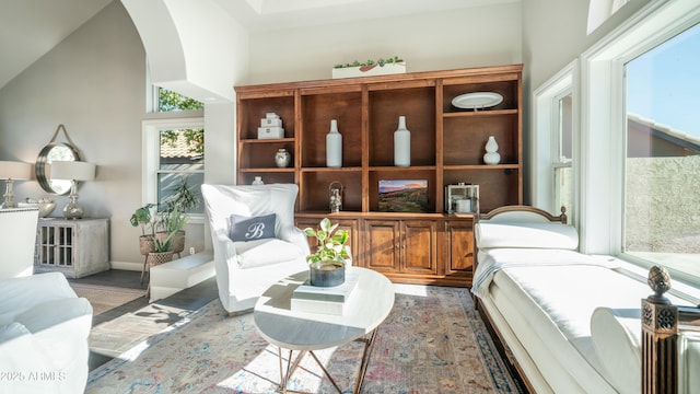 sitting room featuring arched walkways, vaulted ceiling, and wood finished floors