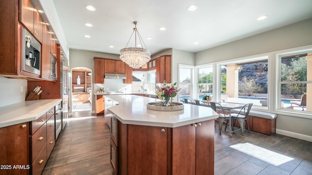 kitchen featuring arched walkways, pendant lighting, light countertops, and a center island