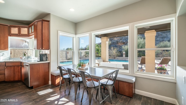 kitchen featuring light countertops, dark wood-type flooring, glass insert cabinets, and brown cabinets