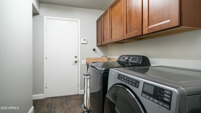 clothes washing area featuring dark wood-style floors, cabinet space, washer and clothes dryer, and baseboards