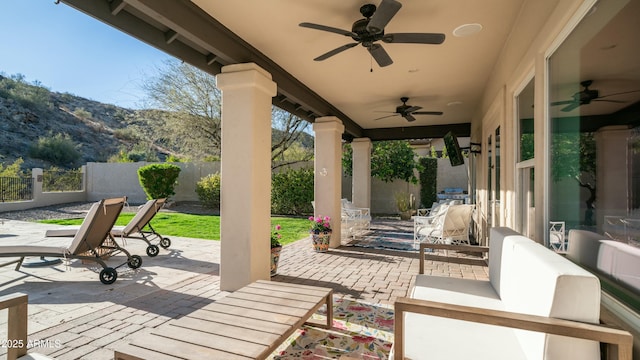 view of patio featuring a ceiling fan, a fenced backyard, and a mountain view