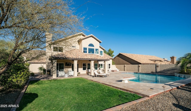 rear view of house featuring a patio, a fenced backyard, a tile roof, a yard, and stucco siding