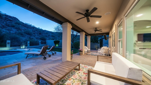 patio terrace at dusk featuring a fenced backyard, a mountain view, a ceiling fan, an outdoor pool, and outdoor dining space