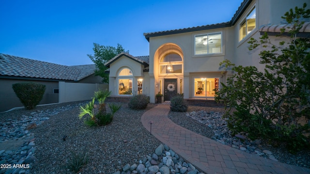 mediterranean / spanish-style house featuring fence, a tiled roof, and stucco siding