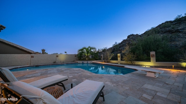 view of swimming pool featuring a fenced in pool, a patio area, a mountain view, a fenced backyard, and a diving board