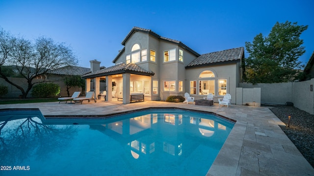 back of property featuring an outdoor fire pit, a fenced in pool, a fenced backyard, a patio area, and stucco siding