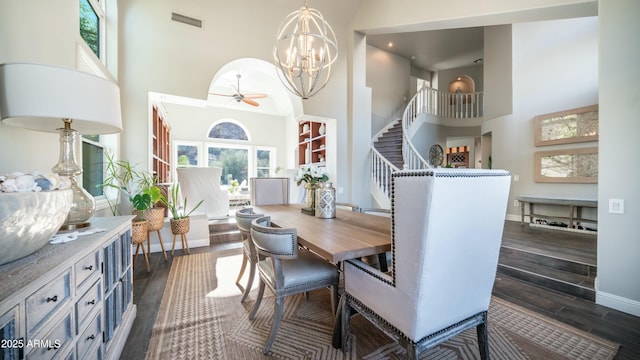 dining area featuring dark wood-type flooring, baseboards, a high ceiling, and stairs