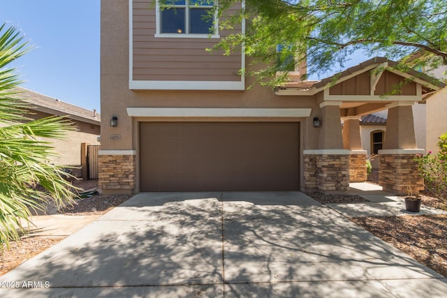 19771 W Woodlands Ave, Buckeye, AZ 85326 - view of front of home featuring stone siding, an attached garage, driveway, and stucco siding