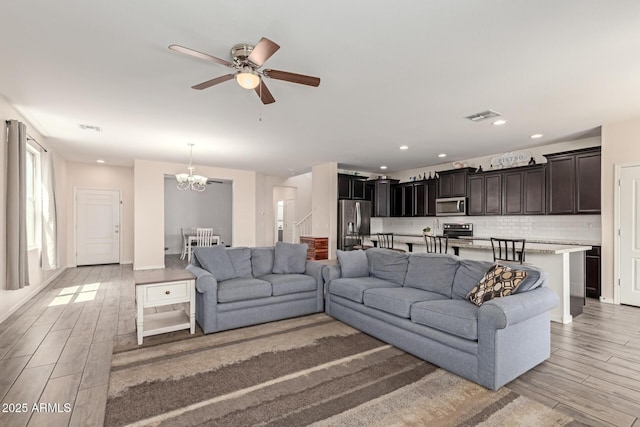 19771 W Woodlands Ave, Buckeye, AZ 85326 - living room featuring a chandelier, light wood-type flooring, a ceiling fan, stairway, and recessed lighting