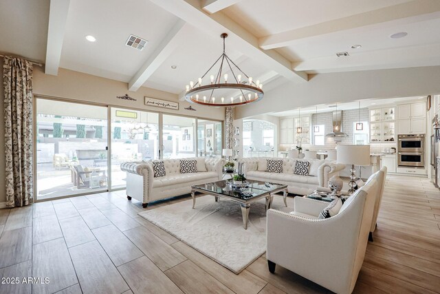 living room featuring visible vents, vaulted ceiling with beams, an inviting chandelier, and light wood finished floors
