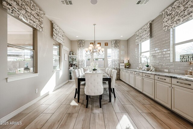dining area featuring an inviting chandelier, visible vents, light wood-type flooring, and baseboards