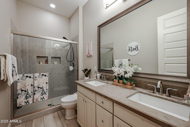 bathroom featuring toilet, a sink, a shower stall, and wood finished floors
