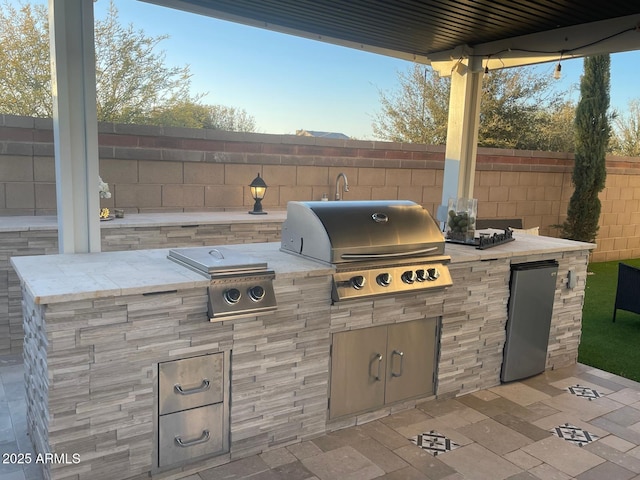 view of patio / terrace with exterior kitchen, a grill, and fence