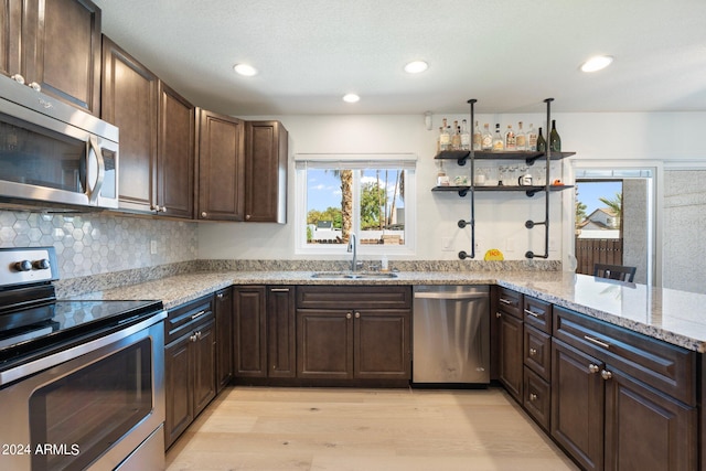 kitchen with light stone counters, stainless steel appliances, sink, and dark brown cabinets