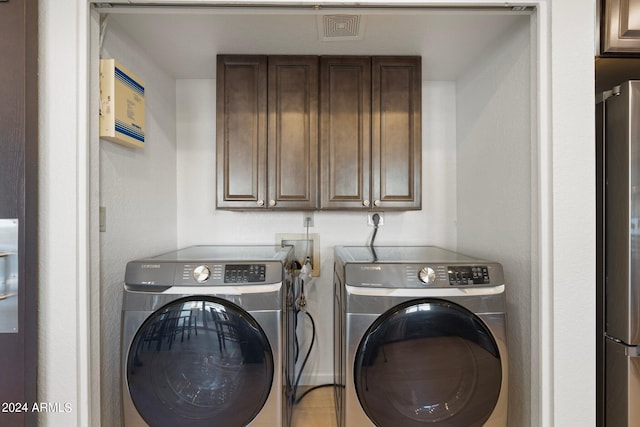 laundry room featuring washing machine and clothes dryer and cabinets