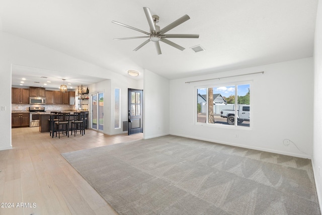 unfurnished living room featuring lofted ceiling, light hardwood / wood-style flooring, and ceiling fan