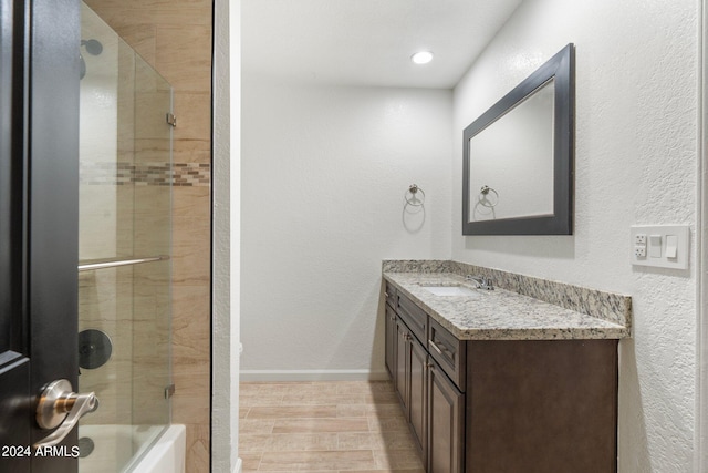 bathroom with enclosed tub / shower combo, wood-type flooring, and vanity