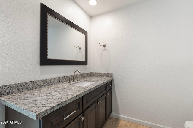 bathroom with vanity, toilet, and hardwood / wood-style flooring