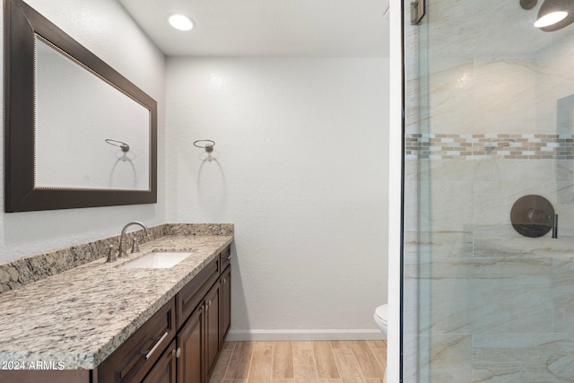 bathroom featuring vanity, toilet, wood-type flooring, and tiled shower