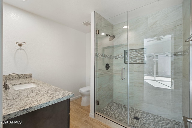 bathroom with an enclosed shower, toilet, hardwood / wood-style flooring, and vanity