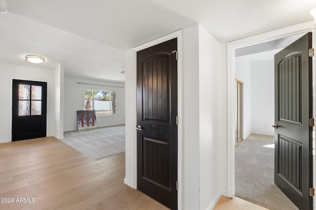 foyer featuring a textured ceiling and light carpet