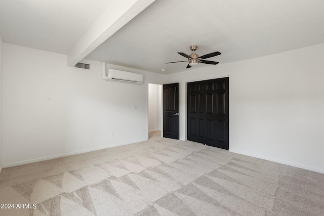 empty room featuring light colored carpet, ceiling fan, a wall unit AC, and beam ceiling