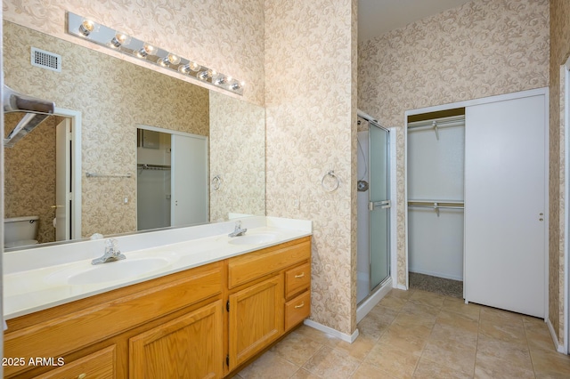 bathroom with toilet, tile patterned flooring, walk in shower, and vanity