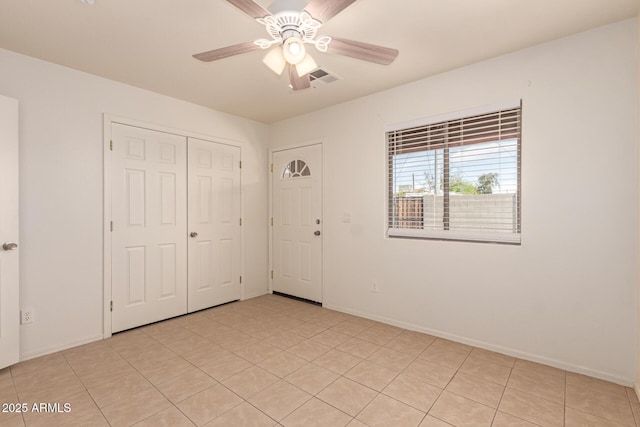 unfurnished bedroom with visible vents, a closet, baseboards, ceiling fan, and light tile patterned floors
