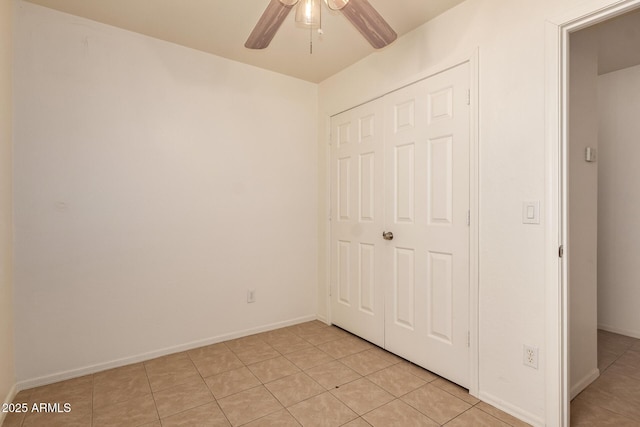 unfurnished bedroom featuring light tile patterned flooring, baseboards, ceiling fan, and a closet