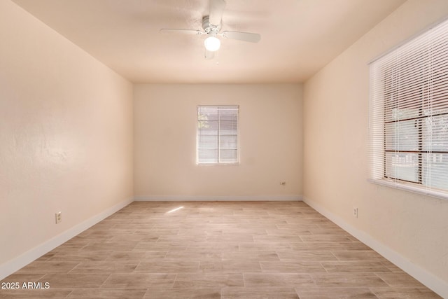 empty room featuring a ceiling fan, a wealth of natural light, and light wood-type flooring