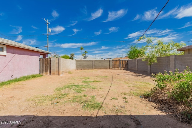 view of yard with a fenced backyard and a gate