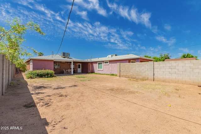 back of property featuring a fenced backyard, central AC unit, and a patio