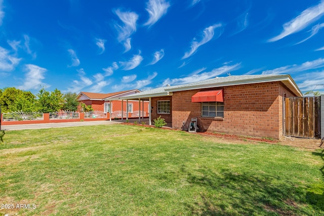 rear view of property with brick siding, a lawn, and fence