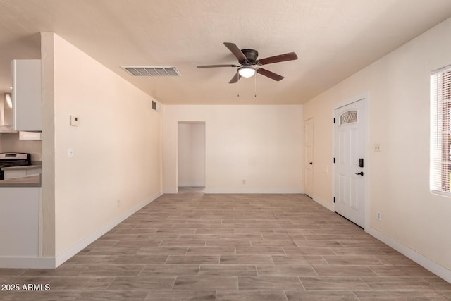interior space with baseboards, ceiling fan, visible vents, and light wood-style flooring
