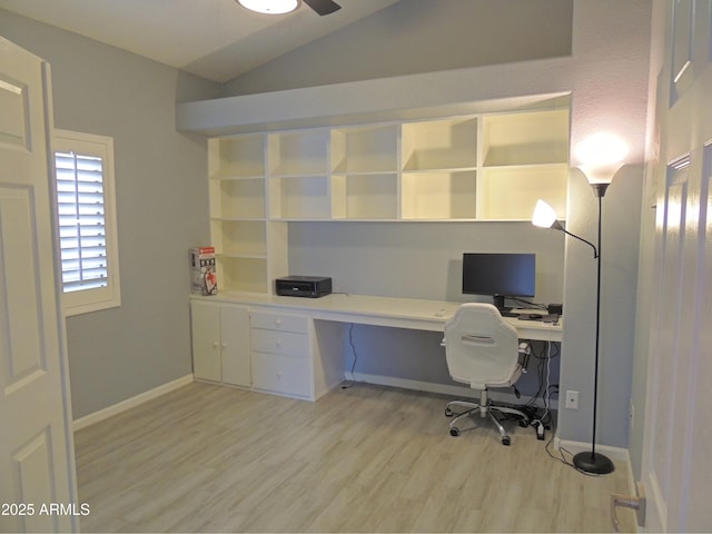 unfurnished office featuring light hardwood / wood-style flooring, built in desk, vaulted ceiling, and ceiling fan