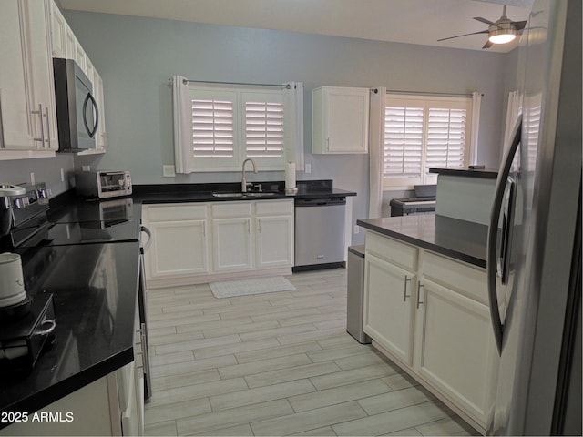 kitchen with appliances with stainless steel finishes, sink, white cabinets, and ceiling fan