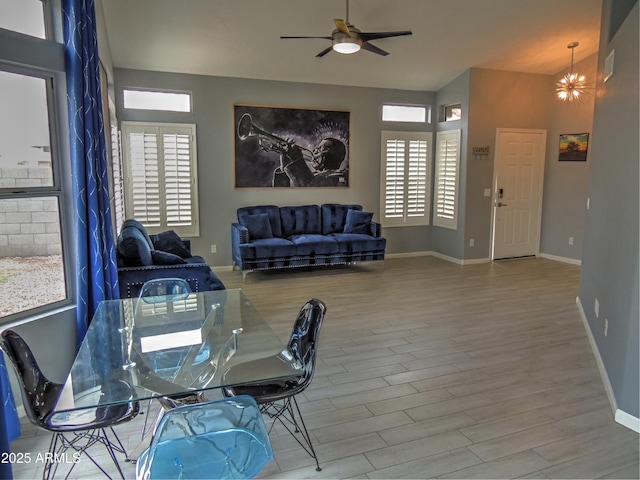 dining space with hardwood / wood-style flooring, vaulted ceiling, and ceiling fan with notable chandelier