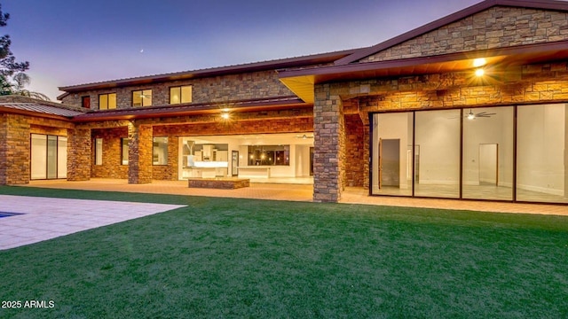 15217 N 15th Dr, Phoenix, AZ 85023 - back of house at dusk with metal roof, a patio, stone siding, and a lawn