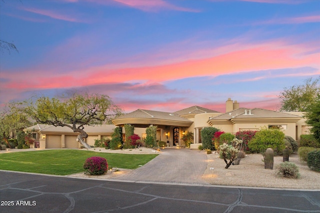 view of front facade featuring a garage, decorative driveway, stucco siding, a front lawn, and a chimney