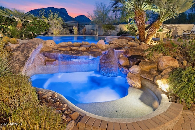 pool at dusk with a mountain view and fence