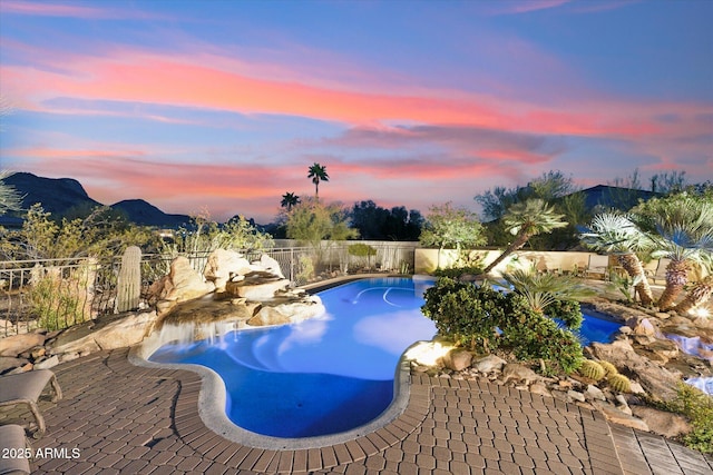 pool at dusk featuring a fenced backyard, a mountain view, a fenced in pool, and a patio