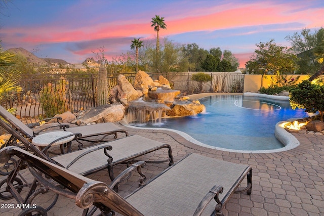 pool at dusk featuring a fenced backyard and a patio