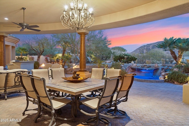 patio terrace at dusk with ceiling fan, outdoor dining space, fence, and a mountain view