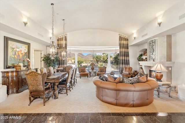 interior space with vaulted ceiling, a premium fireplace, visible vents, and a notable chandelier