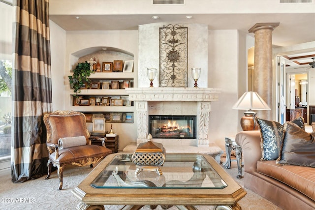 living room with ornate columns, visible vents, built in features, and a high end fireplace