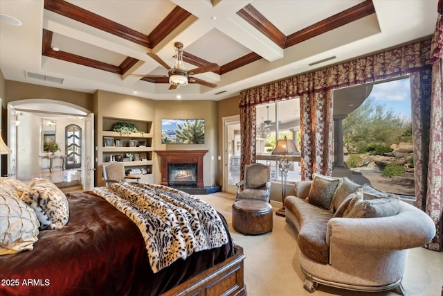 bedroom featuring coffered ceiling, arched walkways, visible vents, and a glass covered fireplace