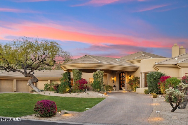 view of front facade featuring stucco siding, a tiled roof, decorative driveway, and a yard