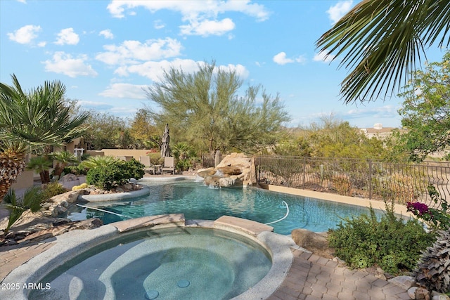 view of swimming pool with fence and a pool with connected hot tub