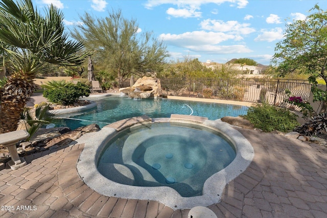 view of pool with fence and a pool with connected hot tub