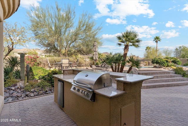 view of patio with fence, grilling area, and an outdoor kitchen